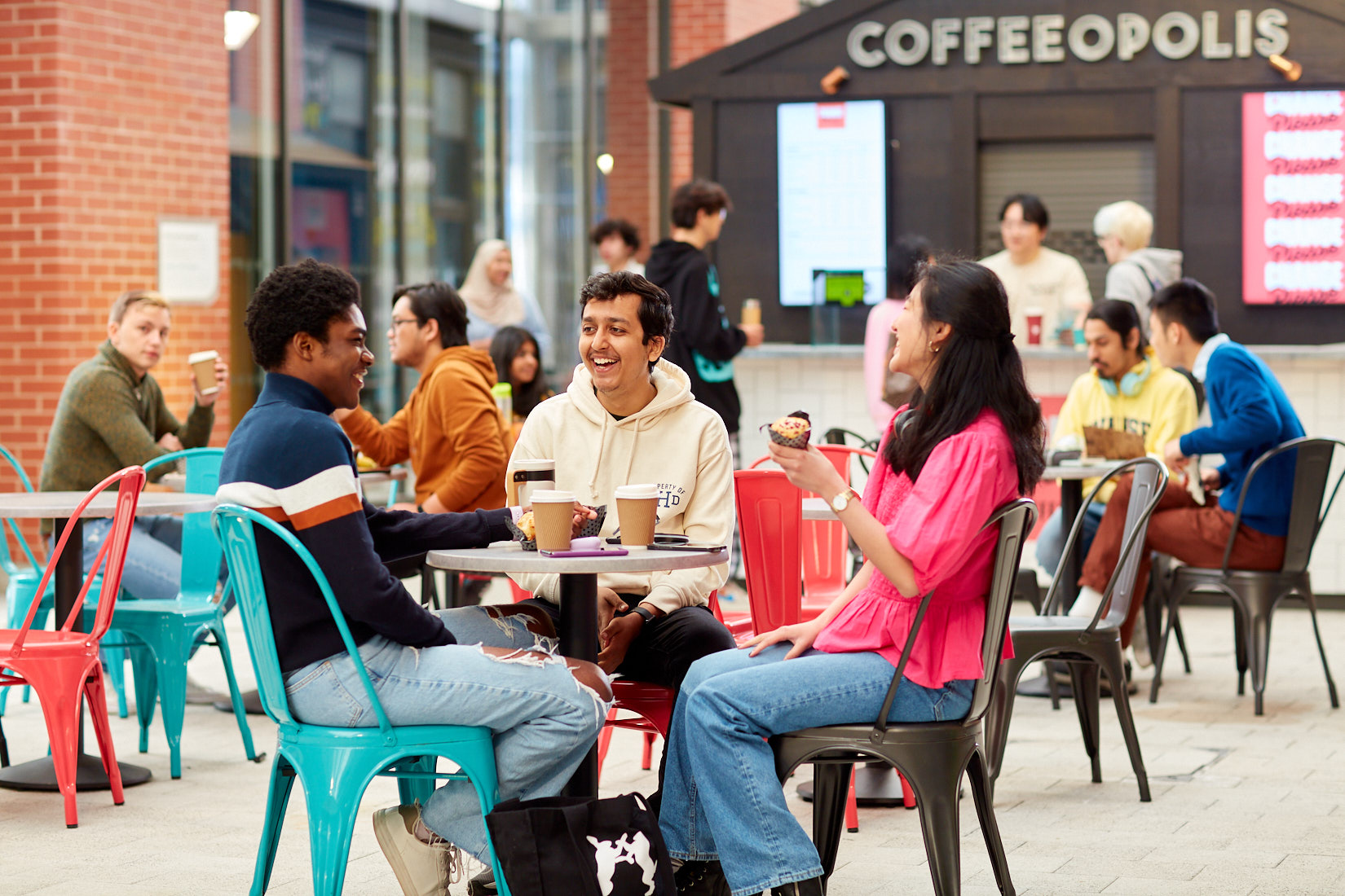 students sitting on chairs outside chatting and smiling