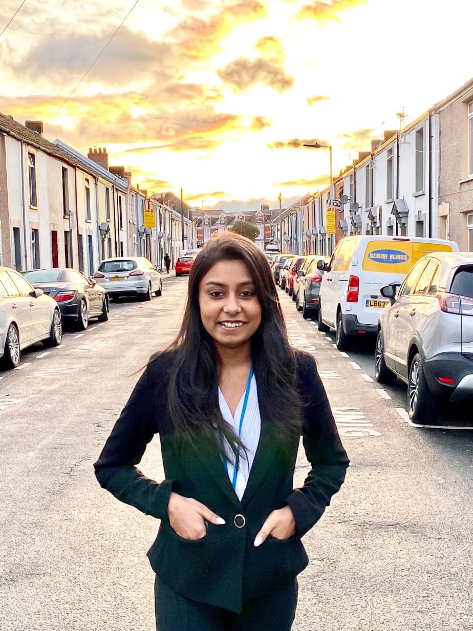 Sakshi smiling with a street of houses in the background