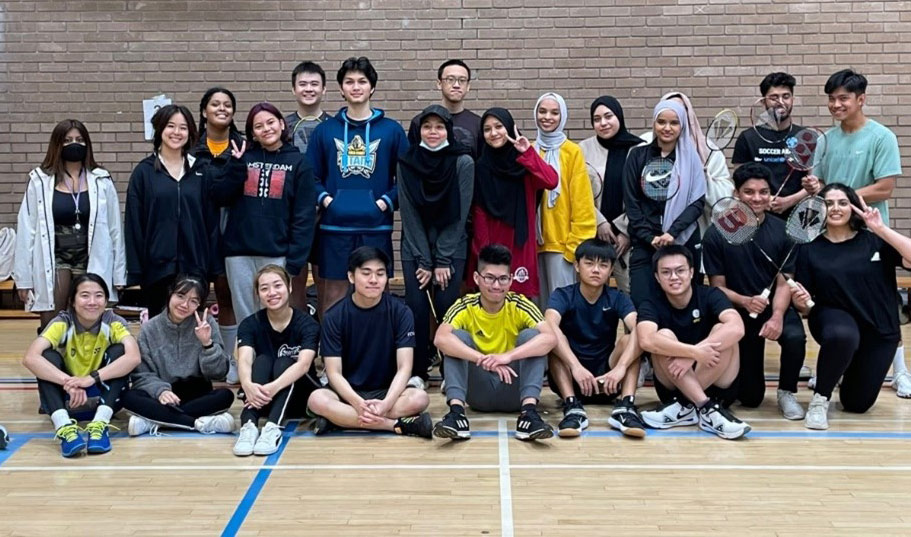 Photo of all about 25 students posing and looking at the camera on a basketball court