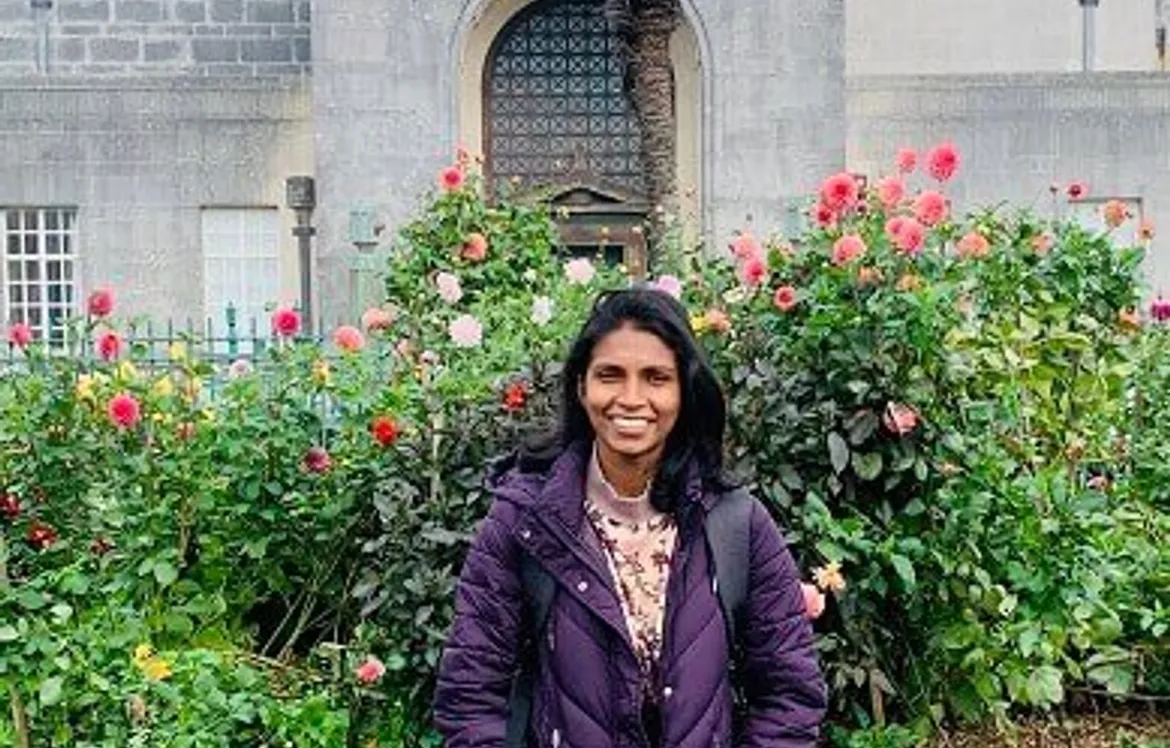 Image of a girl outside in front of a bush.