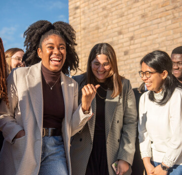 A group of international students laughing, with one of the Bay Campus buildings in the background