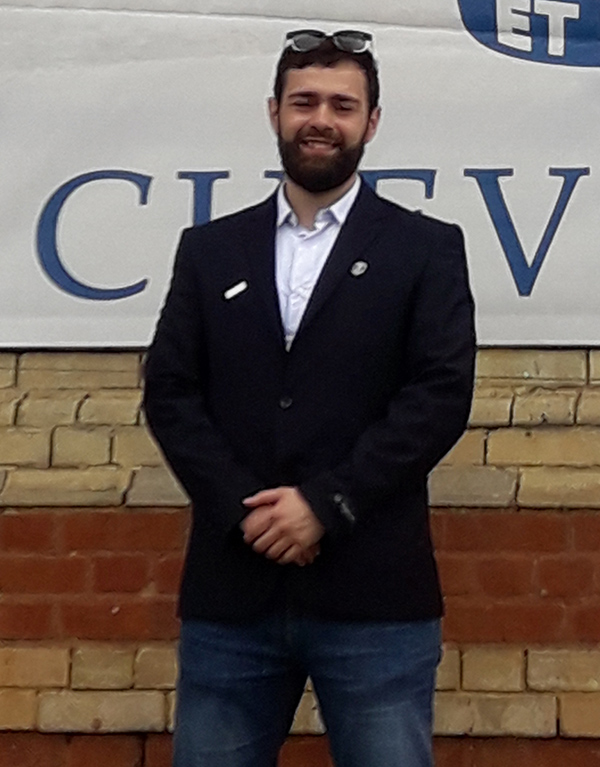 Image of Chevening Scholarship holder, Bilel, standing in front of a Chevening flag.