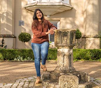 Student standing at the fountain, smiling.