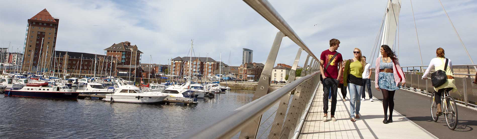 Students walking across a bridge in the Swansea Marina