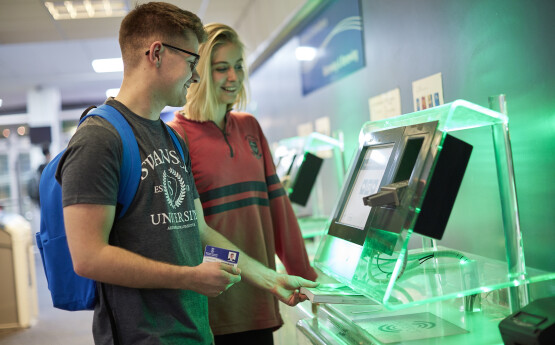 A student borrowing a book at the library self-issue kiosk