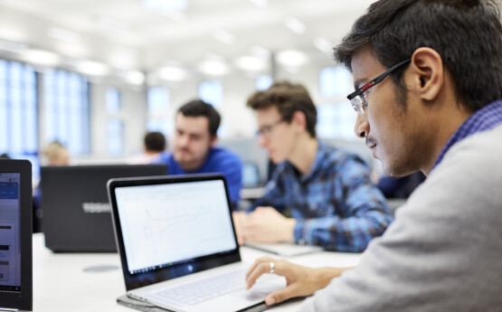 A student using a laptop at a desk in the library