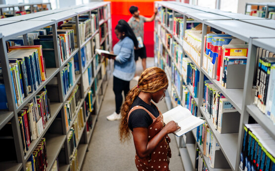 Three students sitting in the back of a white convertible car with Bracelet Bay in the background