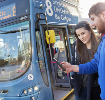 Female and male student getting on the Uni bus.