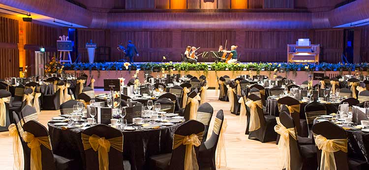 A string quartet practising on the stage with the auditorium prepared ready for a banquet