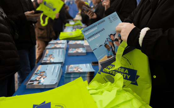 Future students picking up a prospectus at an event.