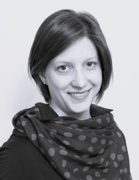 black and white picture of a smiling woman with short dark hair wearing a scarf