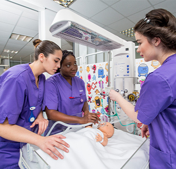 Students learning clinical skills on a baby model 