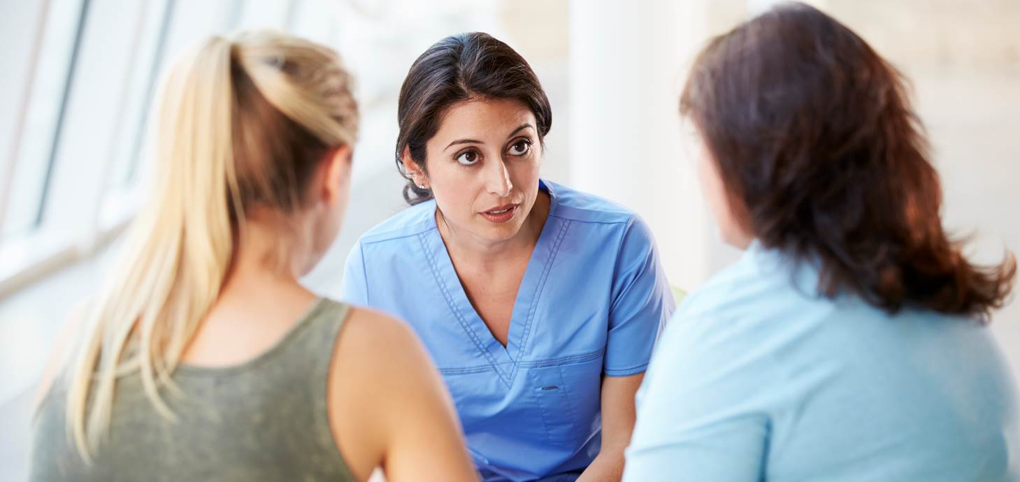 Health professional talking to parent and teenager.