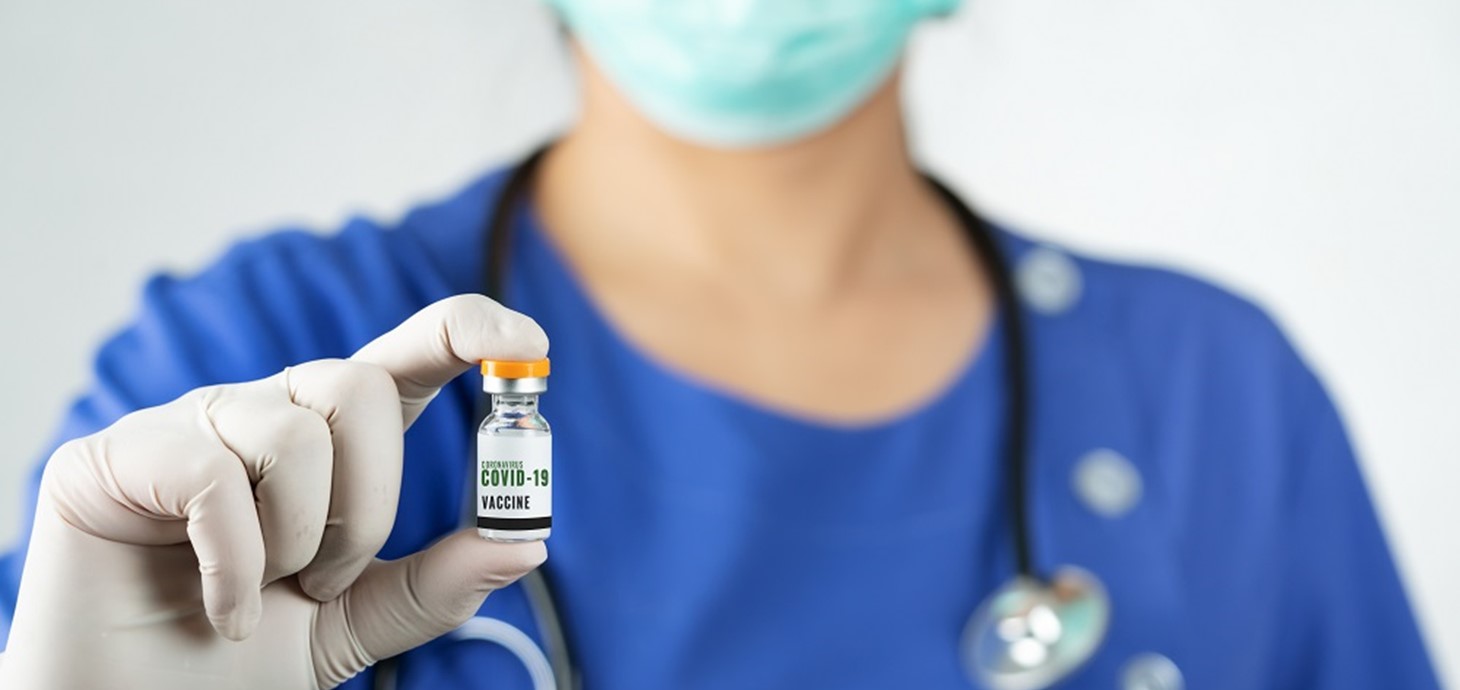 Doctor holding a vial of vaccine; new research finds that no cases of a rare blood disorder have been identified in the COVID-19 vaccinated population of Wales.