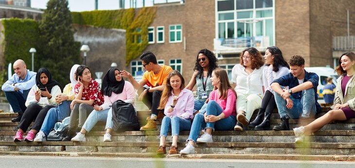 A group of students sitting on the steps in front of Fulton House.