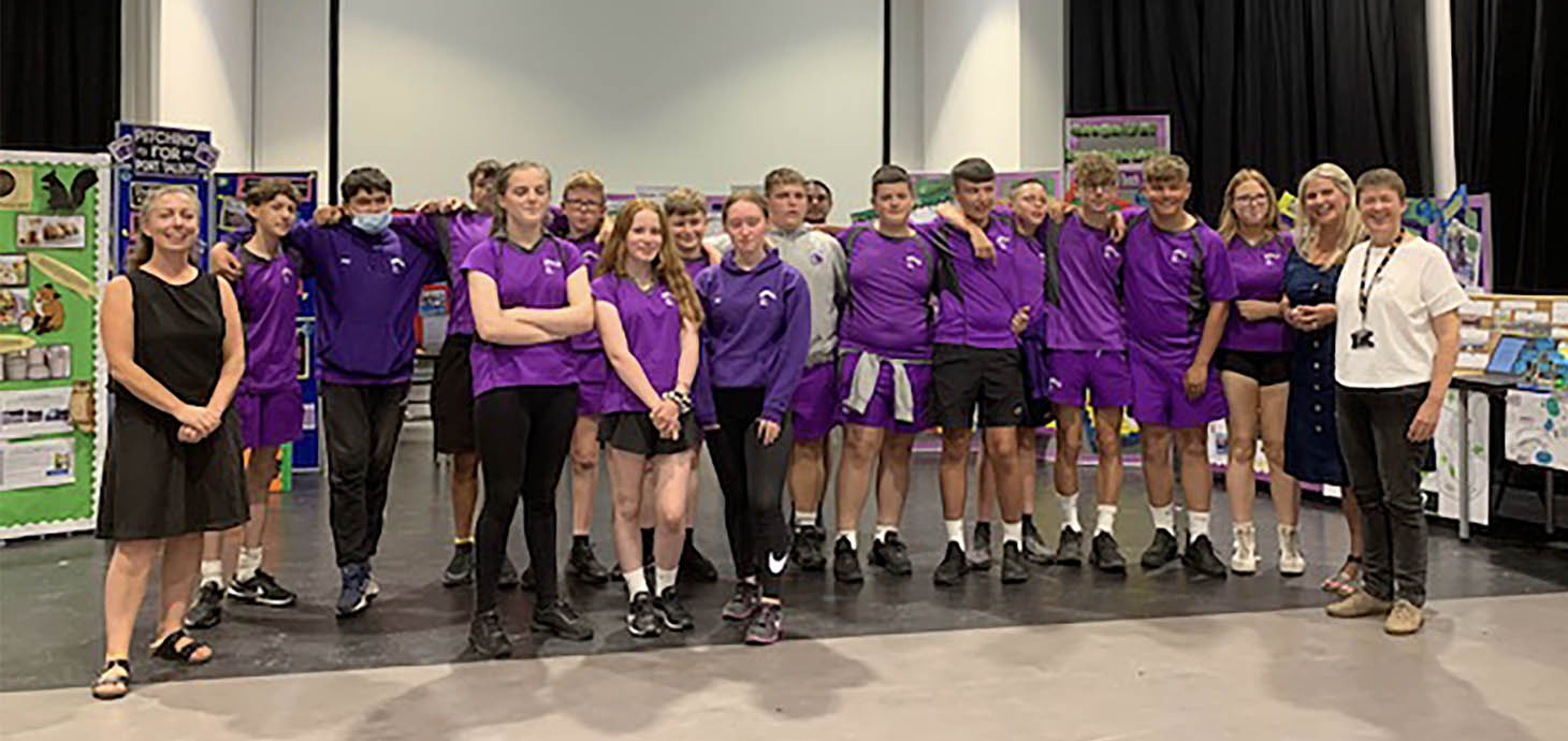 Group of school pupils standing in line in a school hall with two teachers