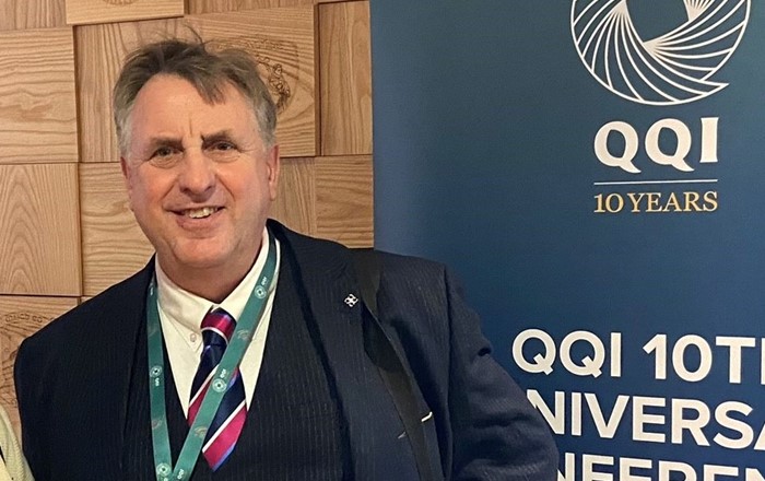 Man in suit and tie standing by a sign for a conference