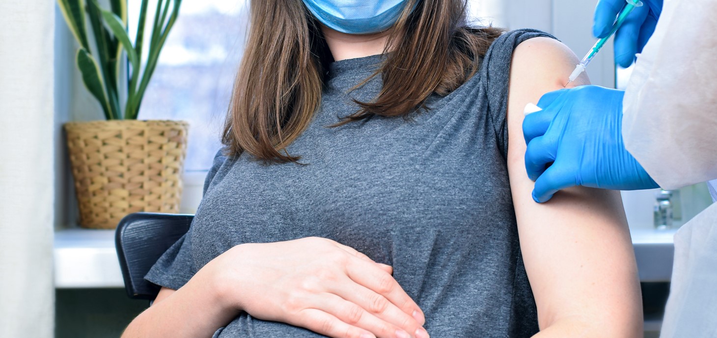 Pregnant woman wearing face mask receiving a vaccination 