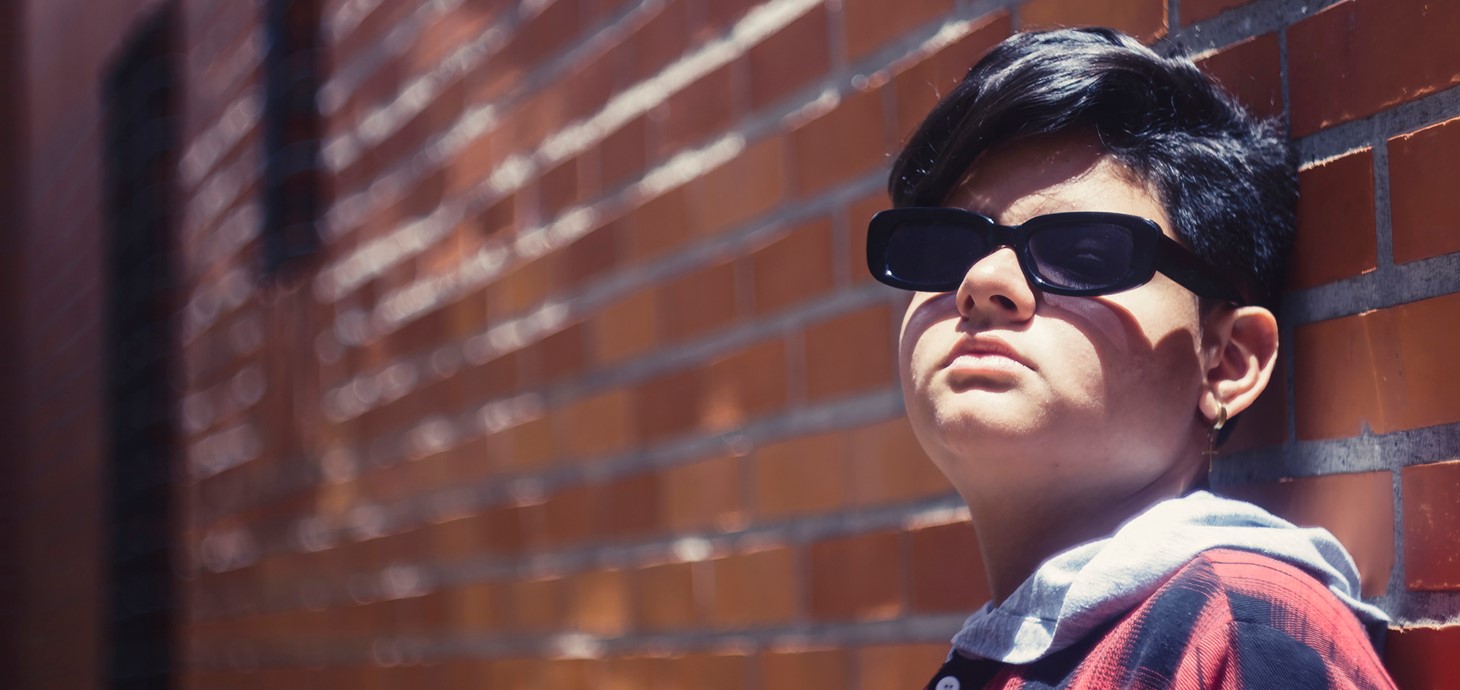 Person standing in front of a wall wearing dark glasses