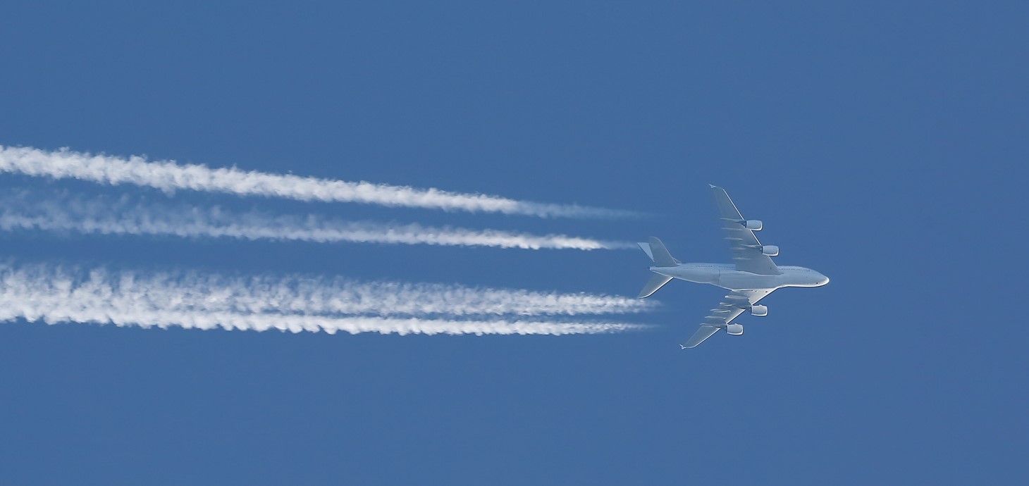 Jet plane pictured flying across a blue sky leaving a series of vapour trails behind