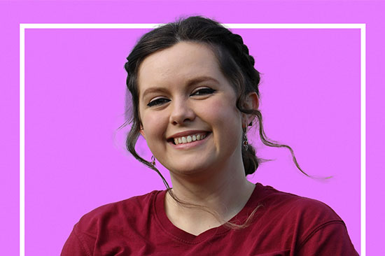 Head and shoulders photo of smiling young woman against a pink background