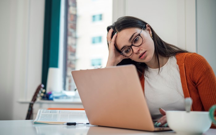 A student with her head in her hand looking at a laptop