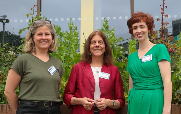 Three smiling women standing in front of a building