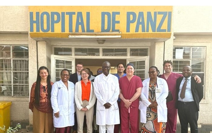 Group of people standing outside a hospital building, some in medical scrubs.