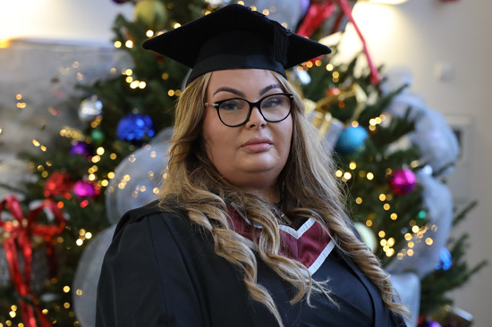 A photo of Holly Williams wearing a cap and gown on the day of her graduation.