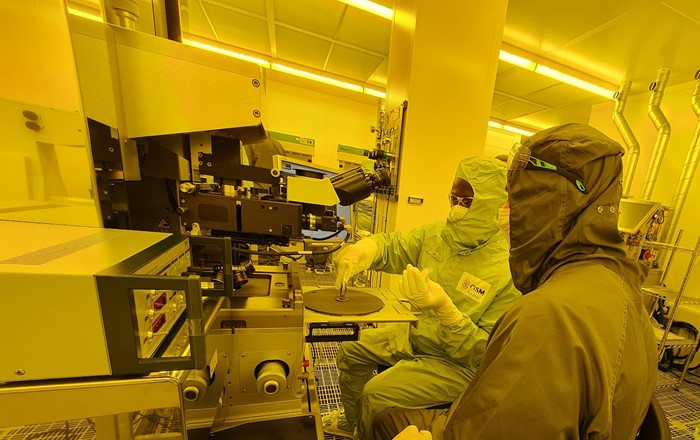 A student and staff member wearing protective clothing work with equipment in the photolithography laboratory.