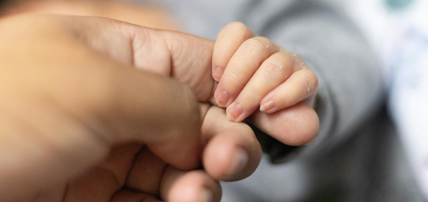 Adult holding a baby's hand