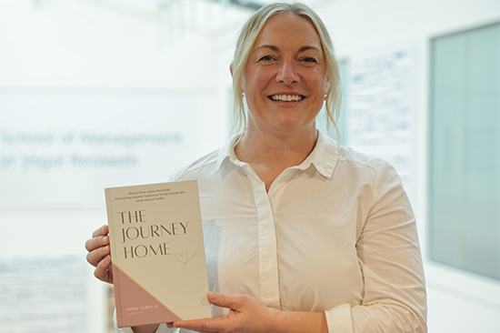 Smiling woman holding up a book
