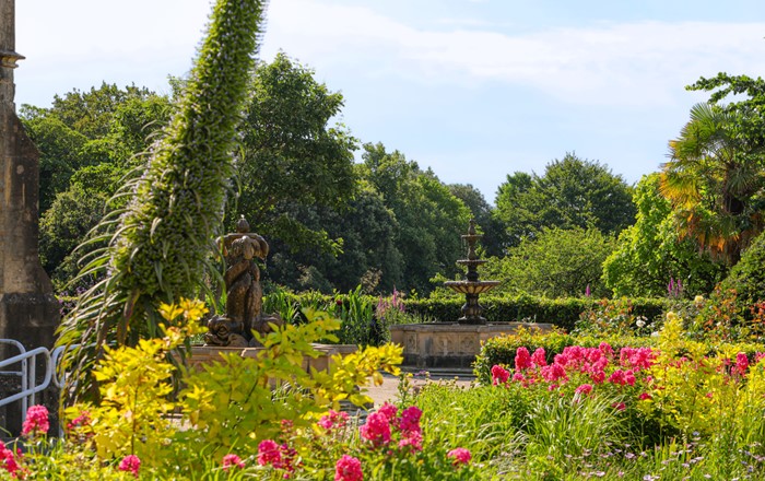 Ornamental garden with flowers, shrubs and stone fountain 