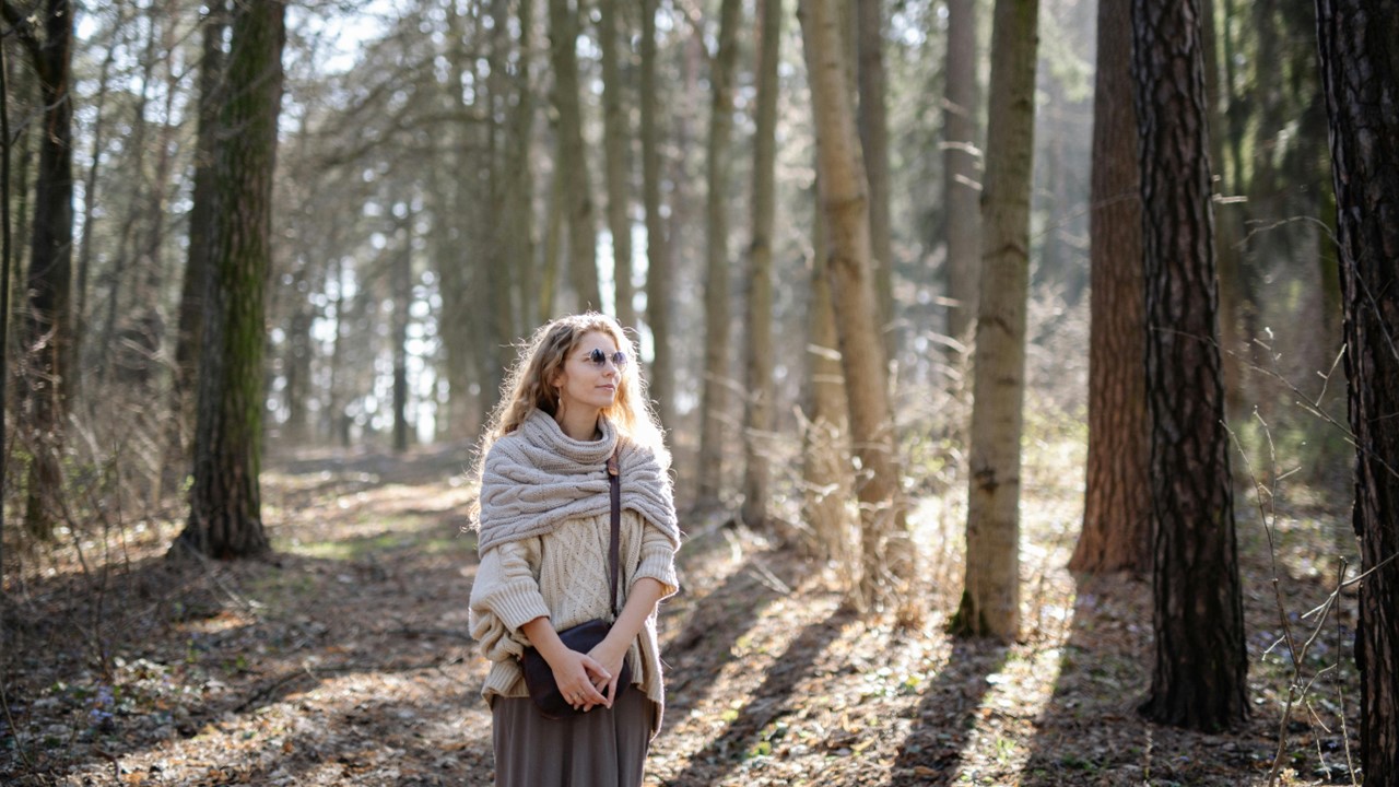 Woman walking along a path in front of trees