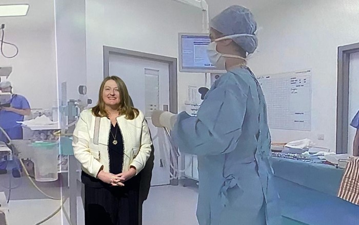 Woman standing in front of wall with image of operating theatre