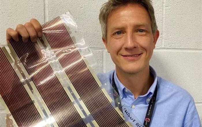 Head and shoulders photograph of a man holding a strip of solar cells