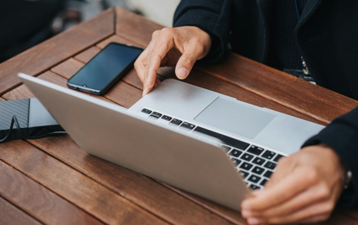 Close up of man's hands with a laptop on a table