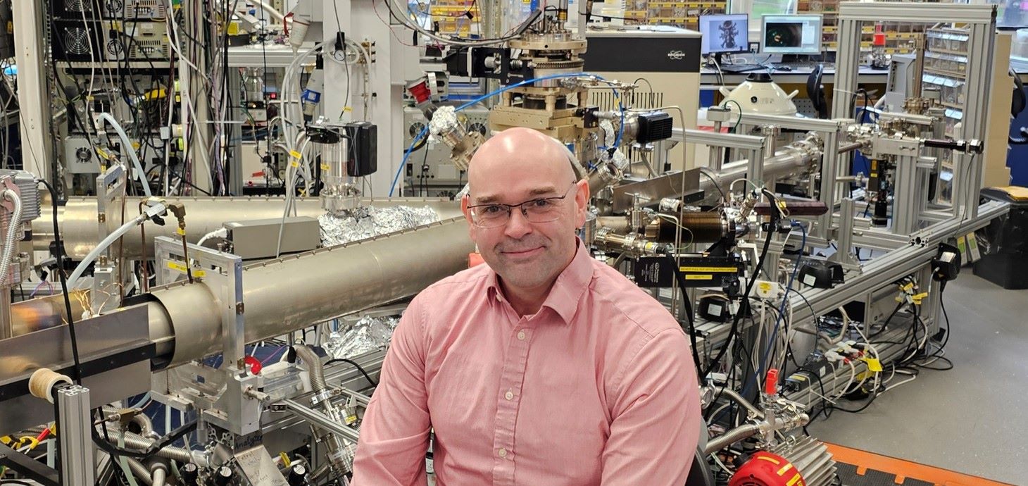 Man sitting in front of equipment in a physics laboratory