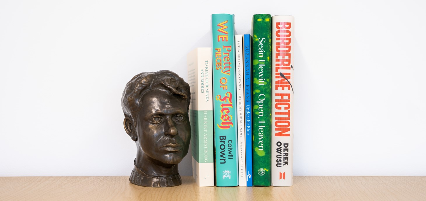 The six shortlisted titles lined up on a bookshelf next to a small bust of Dylan Thomas