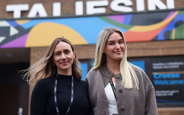 Two women standing side by side outside a building.