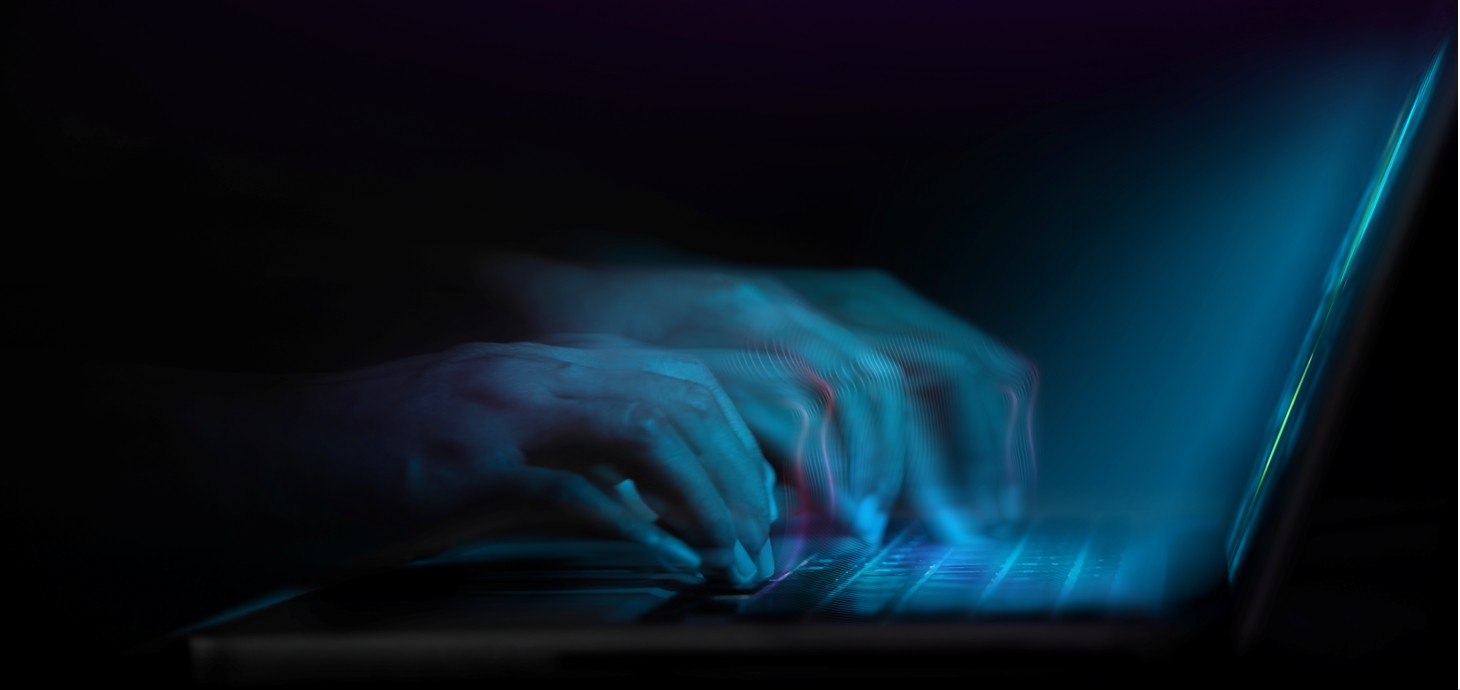 An abstract image of a person's hands typing on the keys of a laptop