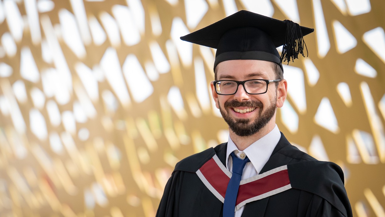 A photo of Jon in his cap and gown at graduation.