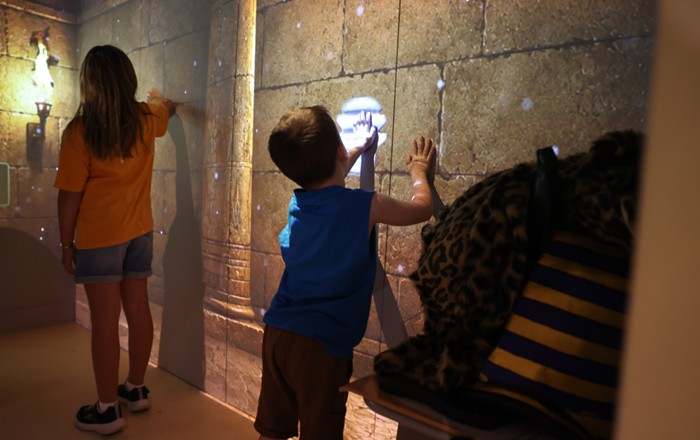 Small boy touching a bright area on an interior wall