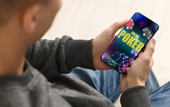 A close-up of a man using a mobile phone to play online poker