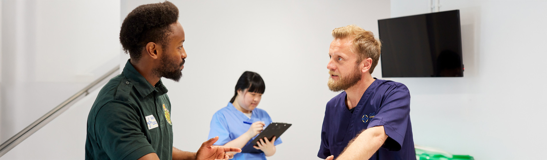 Two men and a woman in medical uniforms talking to each other