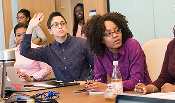 Students in a seminar raising their hands to answer questions