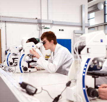 A lecturer having a closer look down a microscope