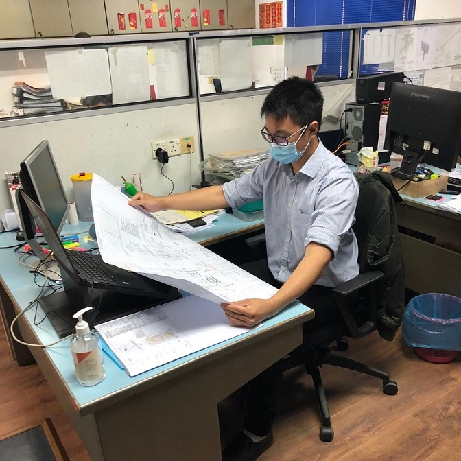 Man sat at a desk with a large document in his hands