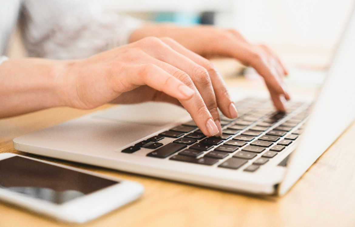 Hands typing on a laptop keyboard