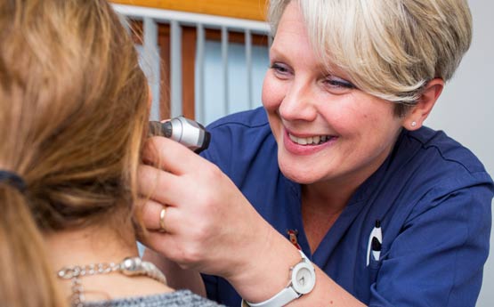 Nursing student looking in a lady's ear